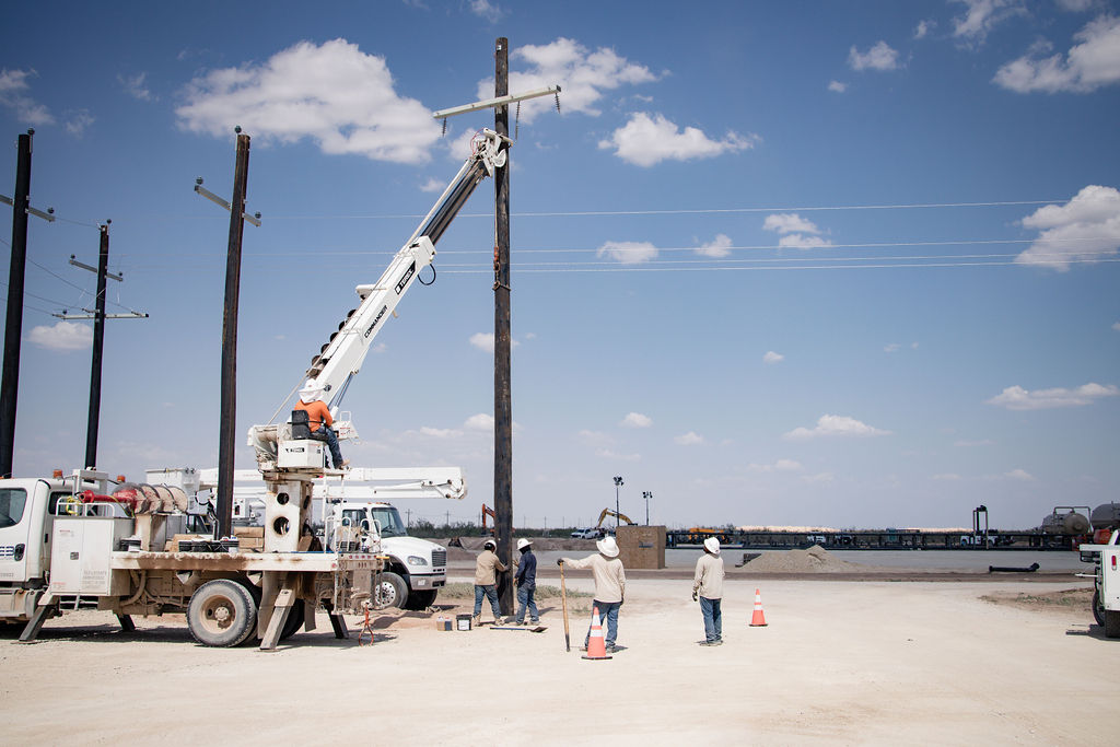 Workers adjusting electrical poles in the field
